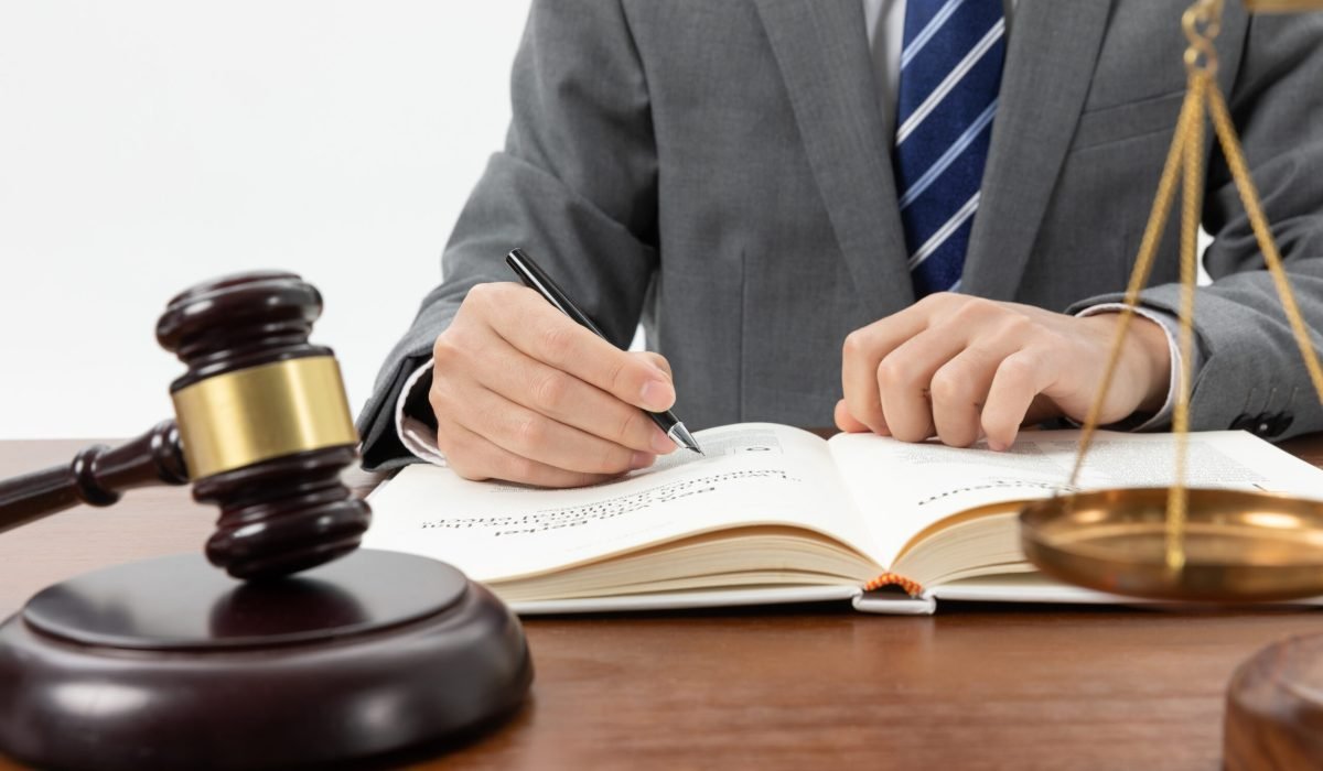 closeup shot person writing book with gavel table